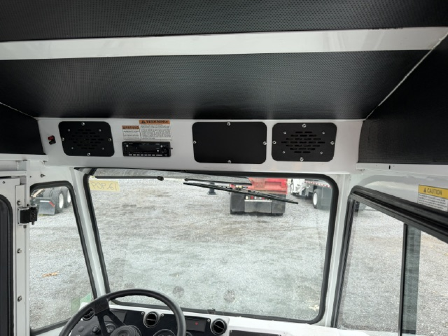 Dashboard area of a TJ6500 yard truck cab showing three vents and control panels above windshield, with warning labels and grille panels.