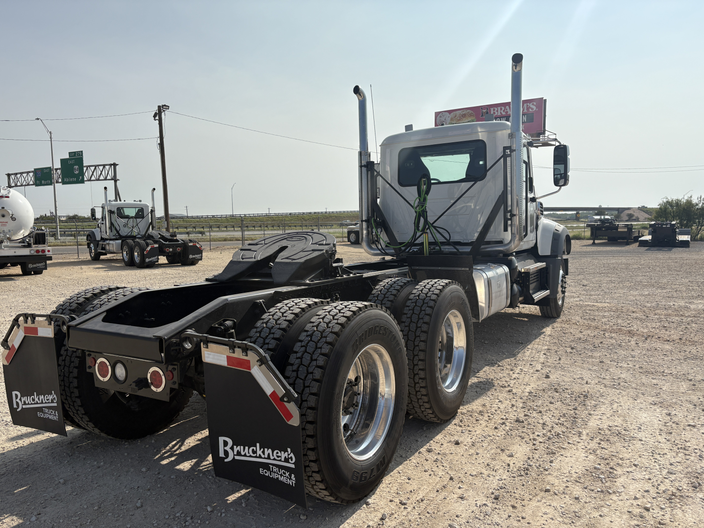 Mack GR64FT truck chassis and cab rear view showing dual rear axles and fifth-wheel area with mud flaps and Bruckner's signage.