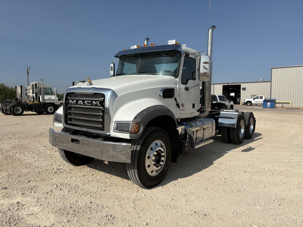 Truck engine bay not visible; front-left view of a white 2027 Mack GR64FT conventional daycab truck on gravel