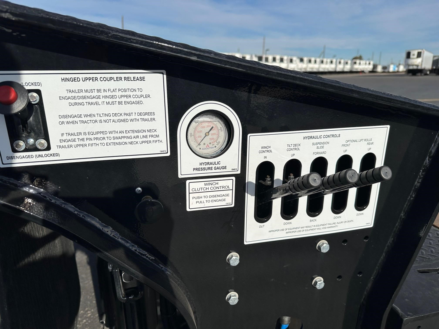 Doepker RT trailer controls panel showing analog pressure gauge and toggle levers with labels and warning stickers.
