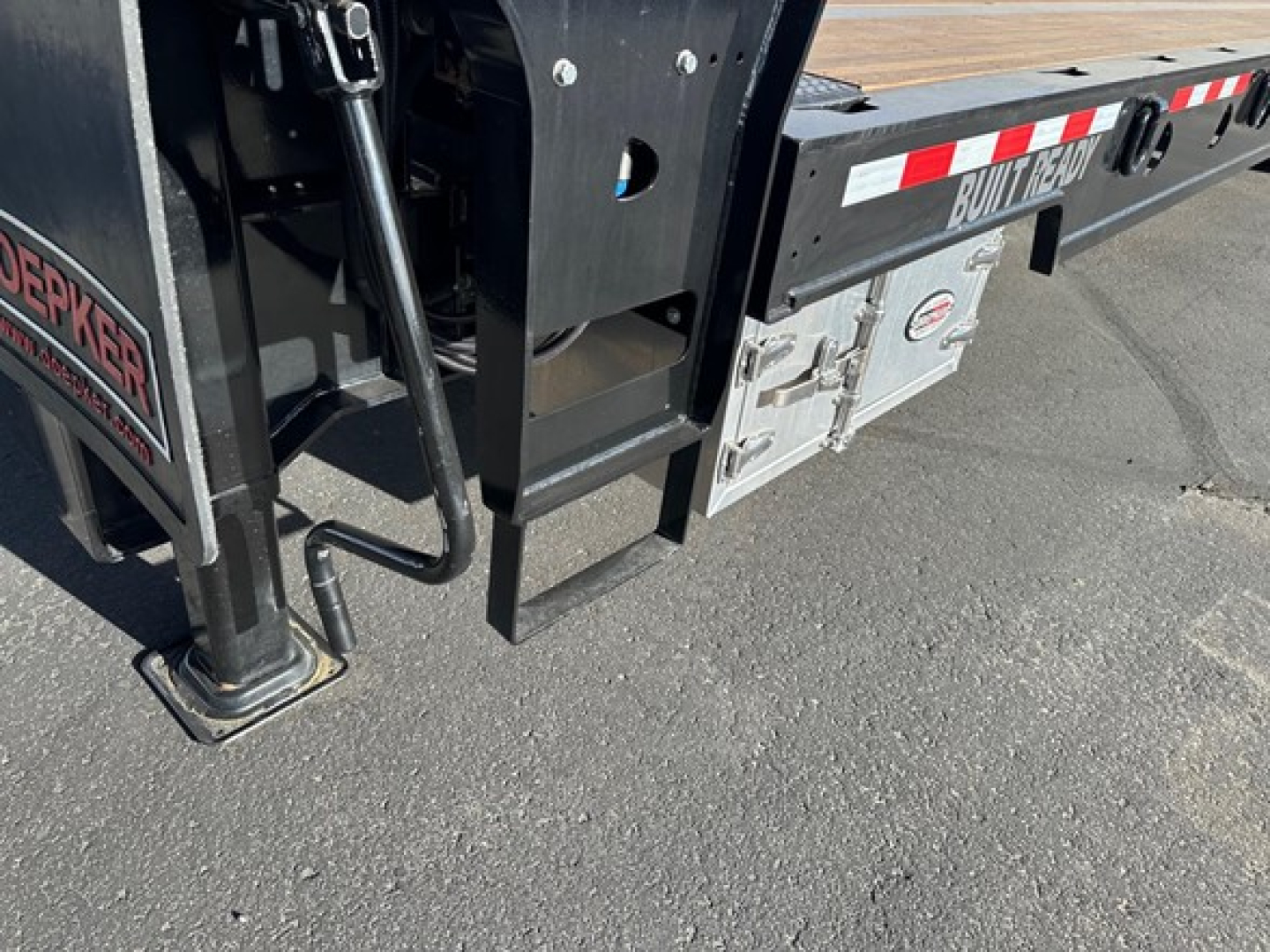 Doepker trailer corner showing support leg, frame and rear storage box with 'BUILT 1230' label and reflective strips.