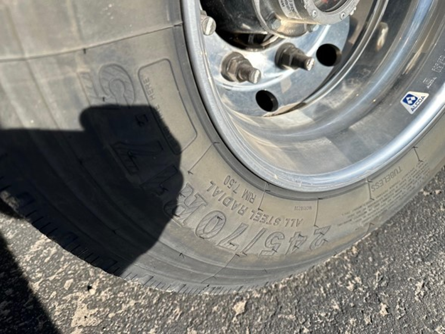 Doepker trailer wheel close-up showing tire with markings, lug nuts, and rim.