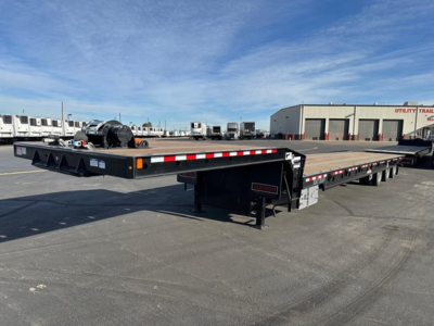 Flatbed trailer showing long low-profile deck with reflective tape and support legs, Doepker branding not visible.