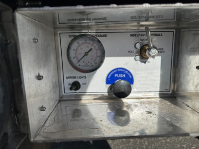 Panel with gauge and control lever inside a Doepker trailer cab. Visible gauge labeled suspension pressure, push button and strobe light switch areas.
