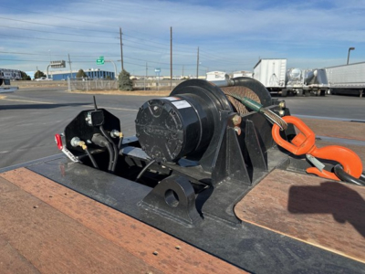 Doepker trailer component on flatbed showing winch hoist with black drum and orange hook and wire rope.