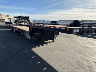 Doepker tridem trailer in a dealership lot showing long flatbed with dual-axle end and equipment on top of the gooseneck area.