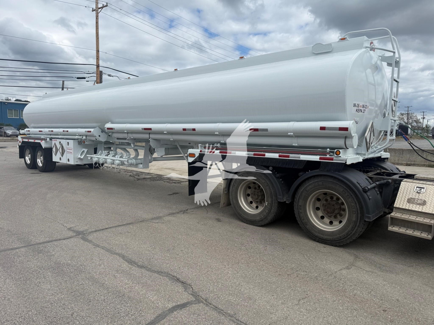 Tank trailer showing cylindrical horizontal fuel tank mounted on a multi-axle trailer with wheels; visible badges and markings on the rear end and side, including small text and reflective strips.