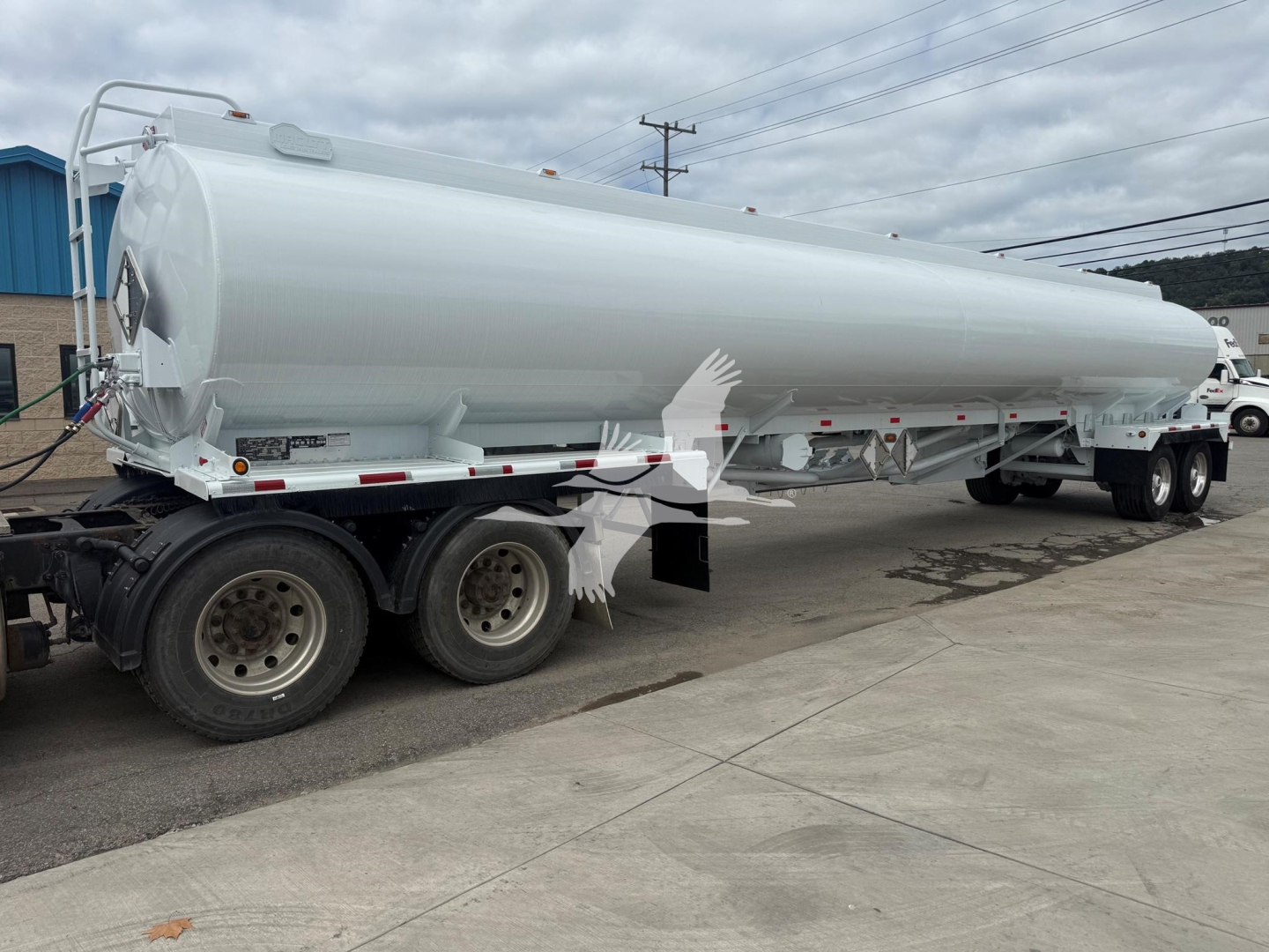Tank trailer showing a cylindrical white Mac Petro fuel tank mounted on a multi-axle trailer. Visible on side: no legible labels from this angle; rear end shows connection hardware and ladders.