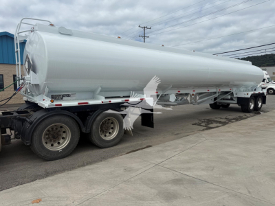 Tank trailer showing a cylindrical white Mac Petro fuel tank mounted on a multi-axle trailer. Visible on side: no legible labels from this angle; rear end shows connection hardware and ladders.