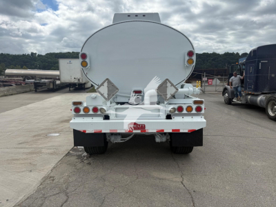 Rear view of a white Mac Petro tank trailer showing circular tank, taillights, and bumper with reflective tape.