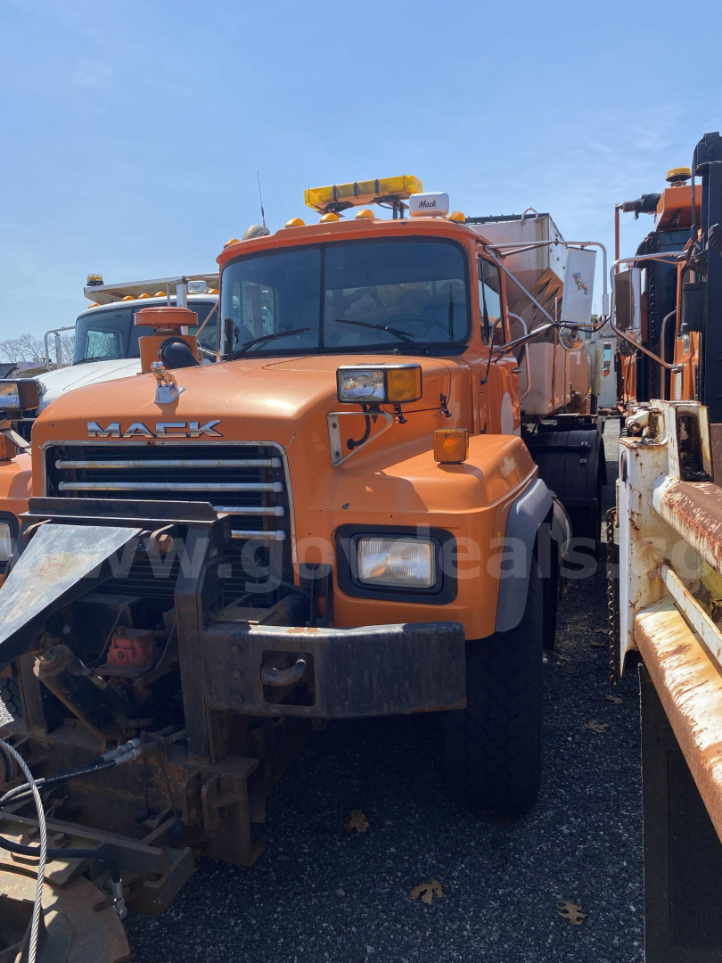 Mack RD688P truck in orange with plow equipment in front, front grille visible, headlights, cab, and utility body; VIN tag not legible.