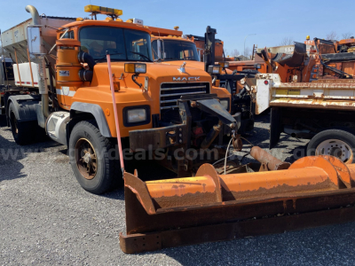 Orange 2004 Mack RD688P truck with plow attachment in a lot of heavy equipment.