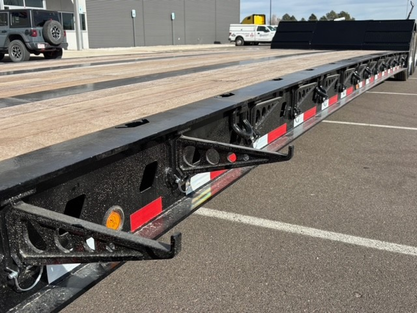 Flatbed trailer with dual swing-out leg and detachable drop structure showing wooden deck and black metal frame.