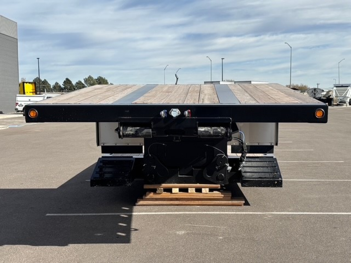 Trailer rear view showing wooden deck and swing-out/double drop mechanism on Alpha A80MG lowboy trailer with hydraulic components and platforms.
