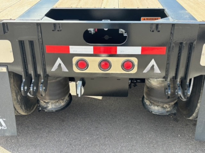 Rear view of 2027 Alpha A80MG lowboy trailer with swingouts and dual drop features, showing rear bumper with red safety lights and circular fender supports.