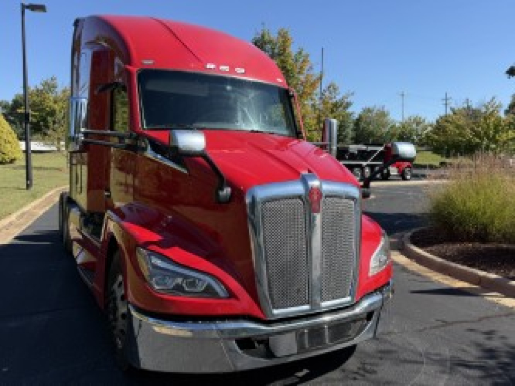 Kenworth T680 conventional sleeper truck in red, front view showing large chrome grille, headlights, and bumper.