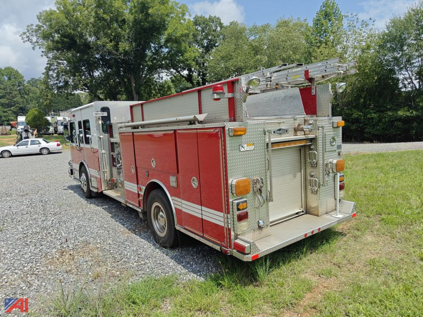 Rear view of a red Spartan fire truck with ladder rack and compartments, aluminum rear bumper, and chrome water hose fittings.