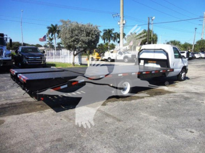 Flatbed tow truck with extended bed and white cab, Ford E-450, side view showing flatbed and rear ramps.
