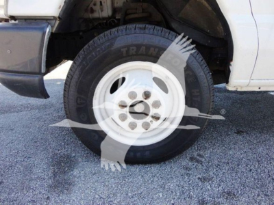 Ford E-Series cargo truck front left wheel showing tire and white steel wheel, fender and front bumper partially visible.