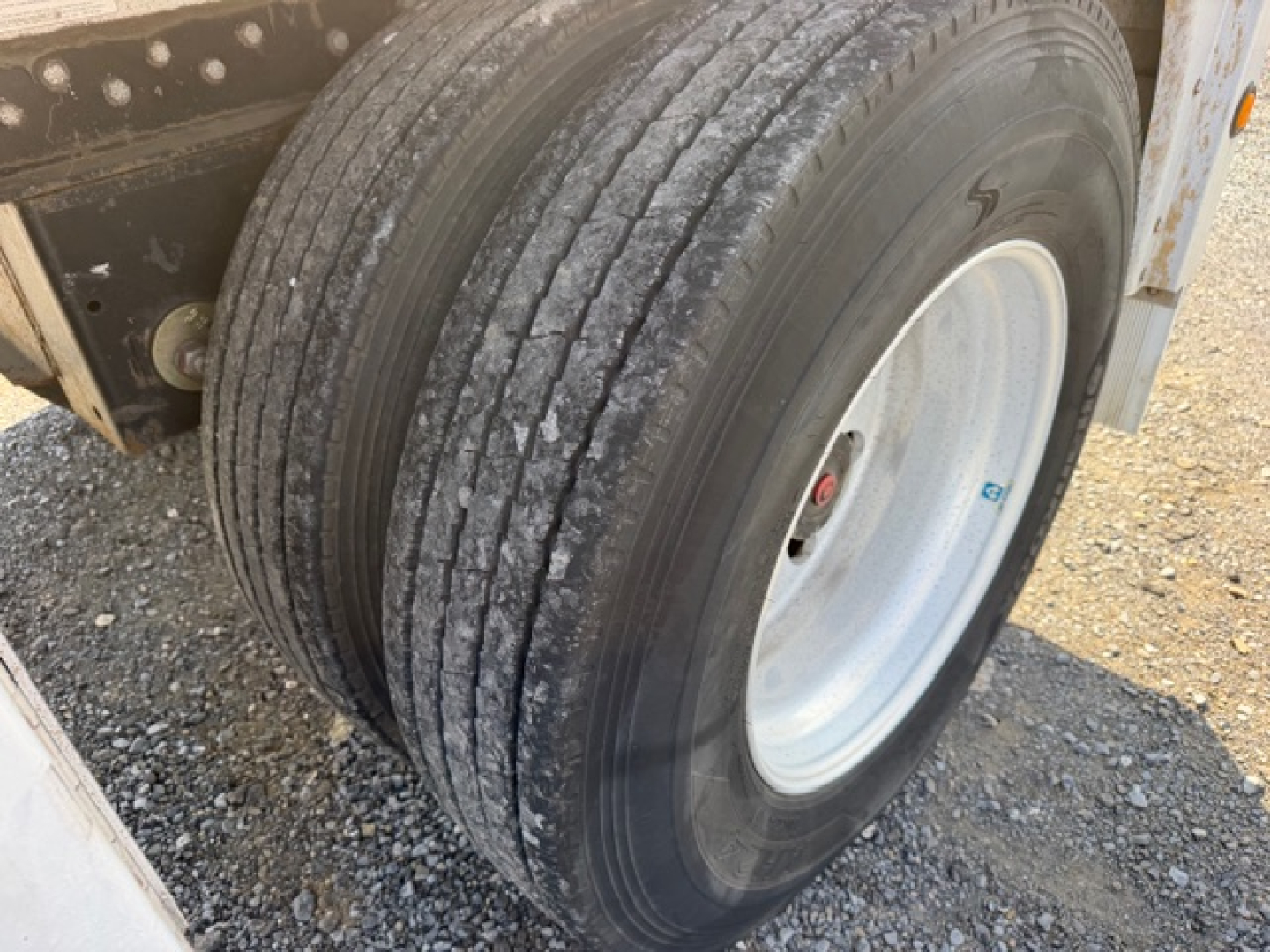 Trailer wheel and dual-tire setup on a flatbed trailer showing the rear tire with tread detail and wheel hub; part of a 2004 Reitnouer MaxMiser 45x96 trailer.