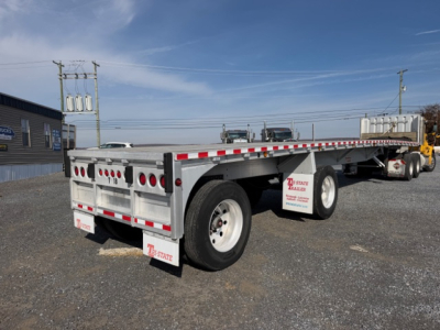 Flatbed trailer shown from rear-left side with dual axles and 45x96 dimensions, white with red/white safety stripes and mud flaps, 2004 Reitnouer MaxMiser tag visible.