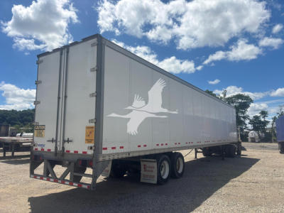 Trailer side view showing large white bird decal on grey Vanguard VXP trailer with dual rear axles and wheel wells.