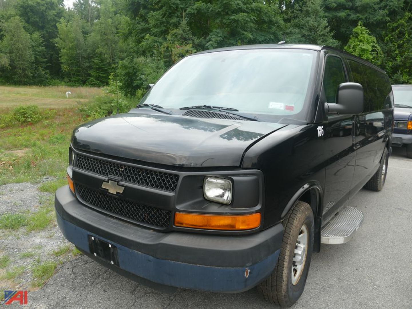 Chevrolet Express LS 3500 extended full-size van, black exterior, front-left view with blue front bumper and step rail, cargo van style</alt_text>