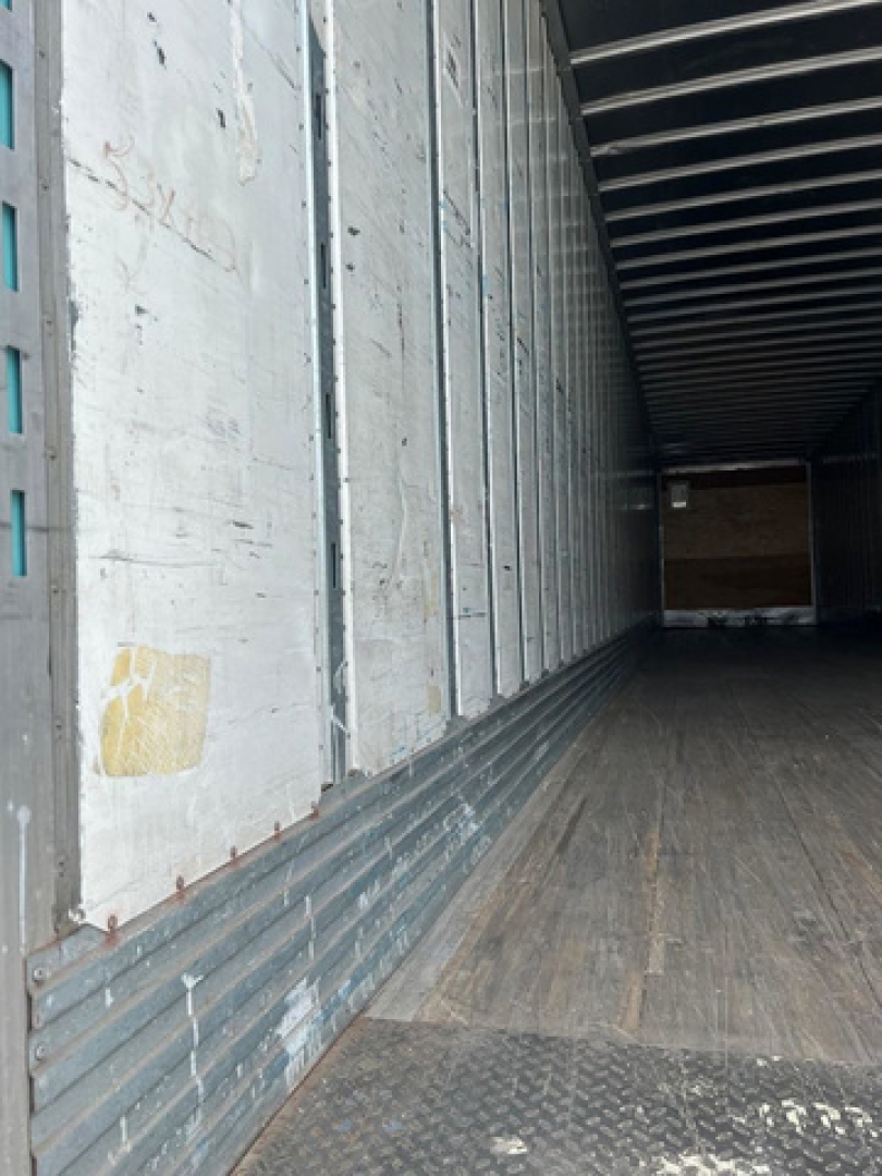 Trailer interior showing empty cargo area with wooden floor and metal side walls.