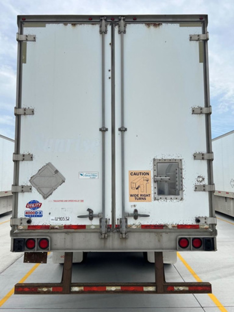 Rear view of a used 2011 utility van trailer with double doors, various stickers, and warning label.