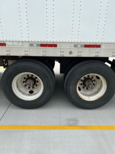 Trailer axle and wheels with dual rear tires visible under a utility van trailer.