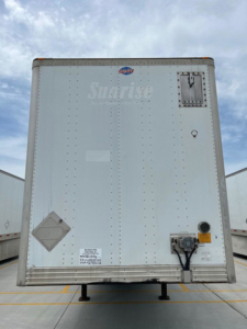 Rear view of a 2011 utility van trailer showing Sunrise branding, access door, electrical plug, and support legs.