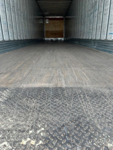 Utility van interior cargo area showing empty long trailer with wooden bulkhead at far end and metal side walls.