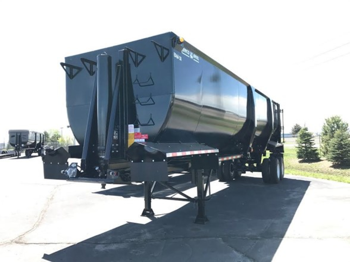Ranco ED60-38 dump trailer mounted on a dual-axle trailer with black finish and raised side rails, viewed from rear-left.