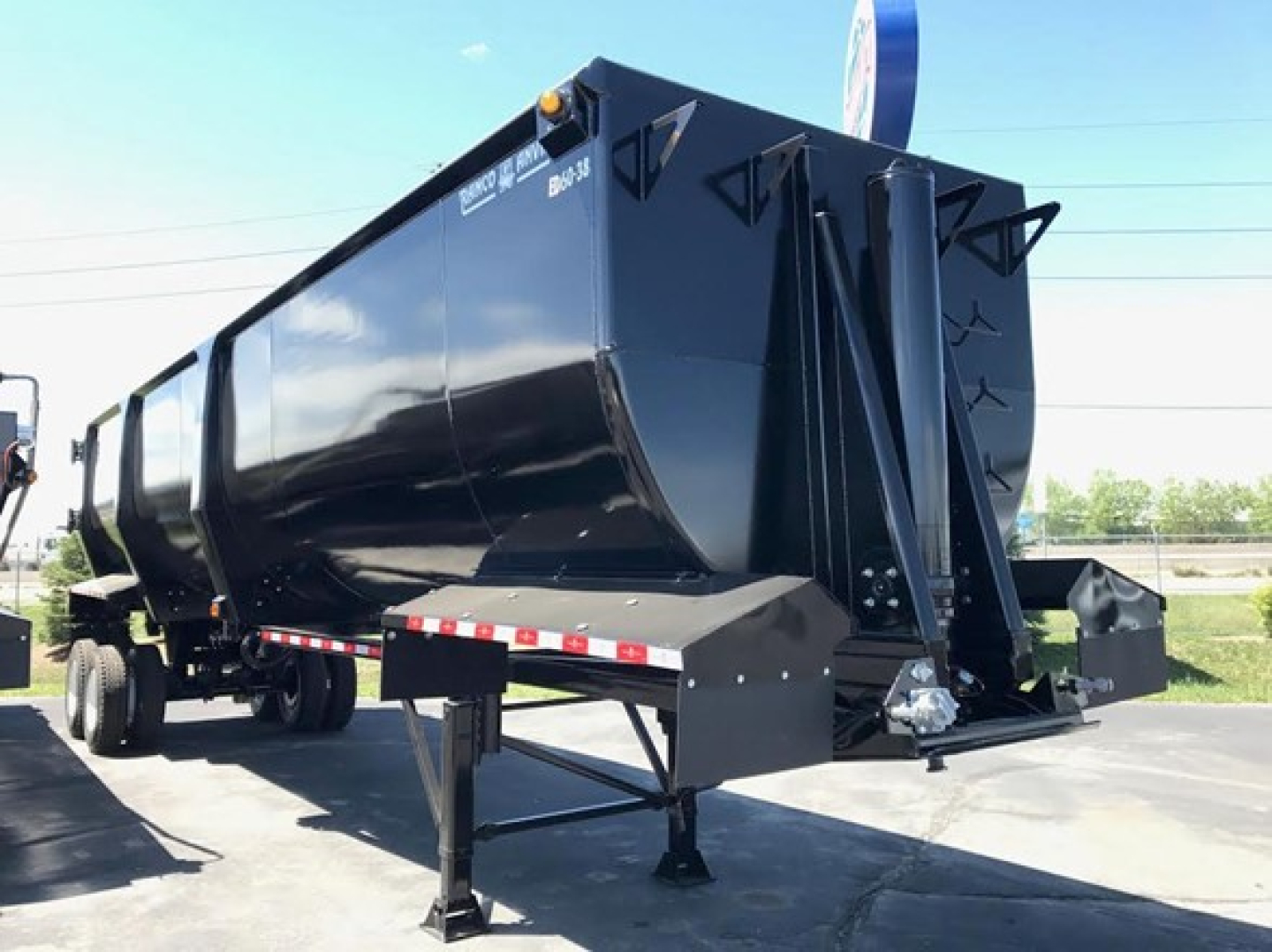 Ranco Ed60-38 dump trailer showing glossy black gooseneck hopper with front landing gear and support legs, side panels, and rear hitch geometry visible.