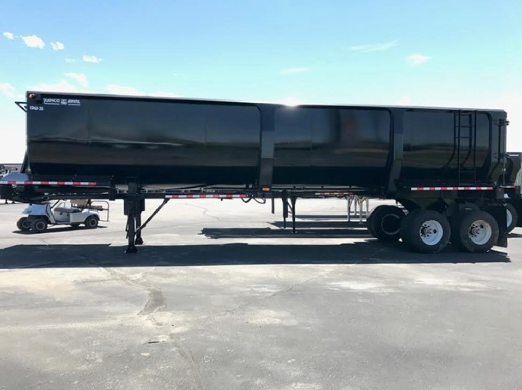 Ranco Ed60-38 dump trailer in side view showing 3-axle rear with black dumping body and white lettering.”