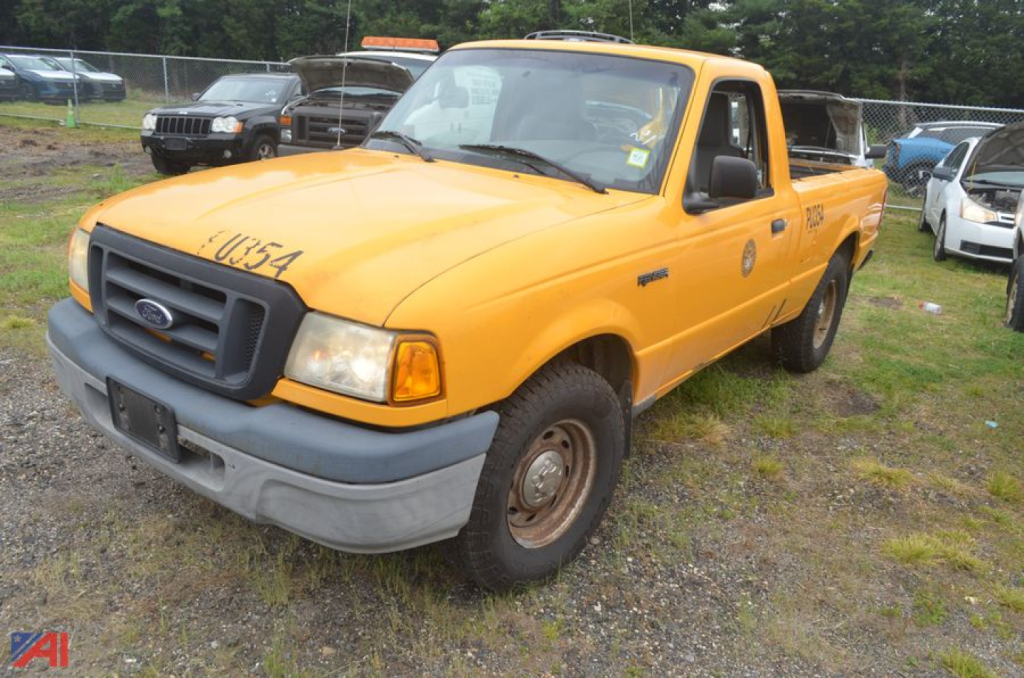 2004 Ford Ranger pickup truck 2wd orange color front-left view with ladder rack and dealership lot in background.