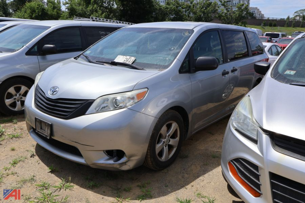 2015 Toyota Sienna minivan in a used car lot, front-left view showing silver body, grille, headlights, and Toyota emblem.