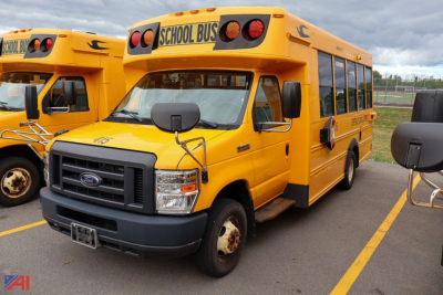 Ford blue bird E-series school bus front-left view showing yellow body, black grille, label 'SCHOOL BUS' on top rear, side doors, and dual mirrors.