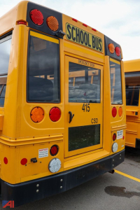 Rear view of a yellow school bus with 'SCHOOL BUS' sign, red and amber lights, and bus number 415; CSD label and emergency exit window visible.