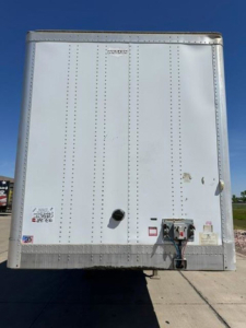 Rear view of a white 2013 Wabash trailer van showing doors, riveted aluminum panels, and rear bumper with electrical service box.
