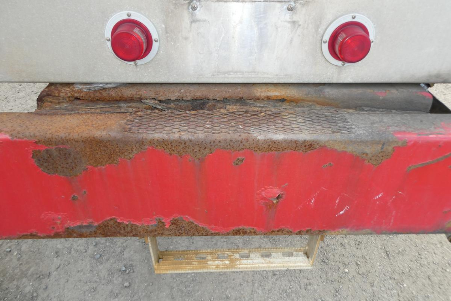 Rear view of 1999 Sterling L7500 truck showing rusted bumper, red reflective taillight housings, and exposed step plate.