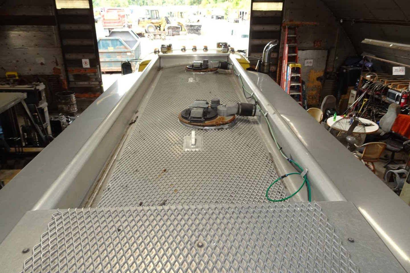 Truck bed view of a Sterling L7500 fuel truck showing a diamond plate surface, circular hatches, and hoses along the sides.