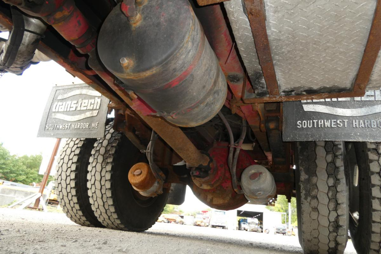 Underbody view of a Sterling L7500 dump truck showing rear axles, fuel tank, exhaust, and mud flaps with 'TransTech' and 'Southwest Harbor' text visible.