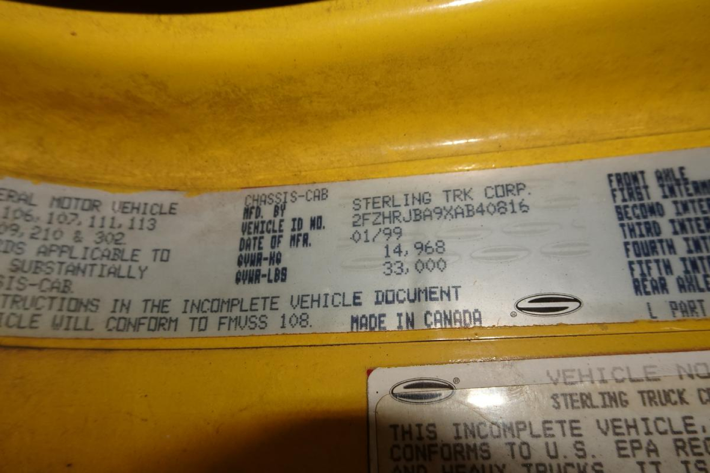 Label showing VIN and vehicle information: 'STERLING TRK CORP' and various weights and markings; text is small and dense across a metal plate.
