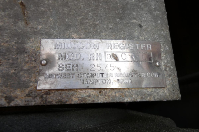 Metal plate with embossed text: MID-COM REGISTER MOD. RH? SER. 2575? then WESTERN COMPUTER REGISTER CO. HAMPTON, IOWA.