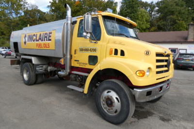 Sterling L7500 gasoline truck with bright yellow cab and Nicholson tank. Side shows INCLAIRE FUEL OILS and US DOT numbers, fuel tank with metallic piping and steps visible.