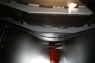 Interior view of a truck bed shield or cargo area with dark metallic surfaces and a central wooden or dark-colored strip.