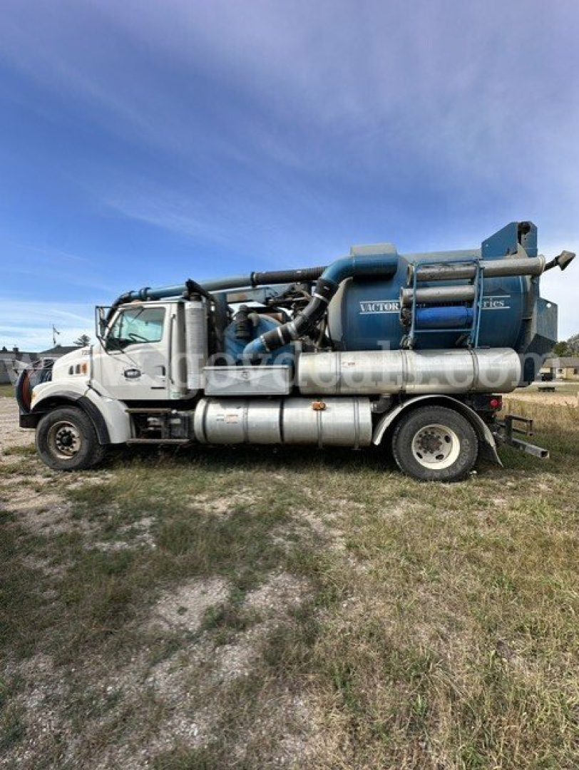 Sterling L7501 vacuum truck side view showing large blue vacuum tank and silver fuel tanks with cab in foreground