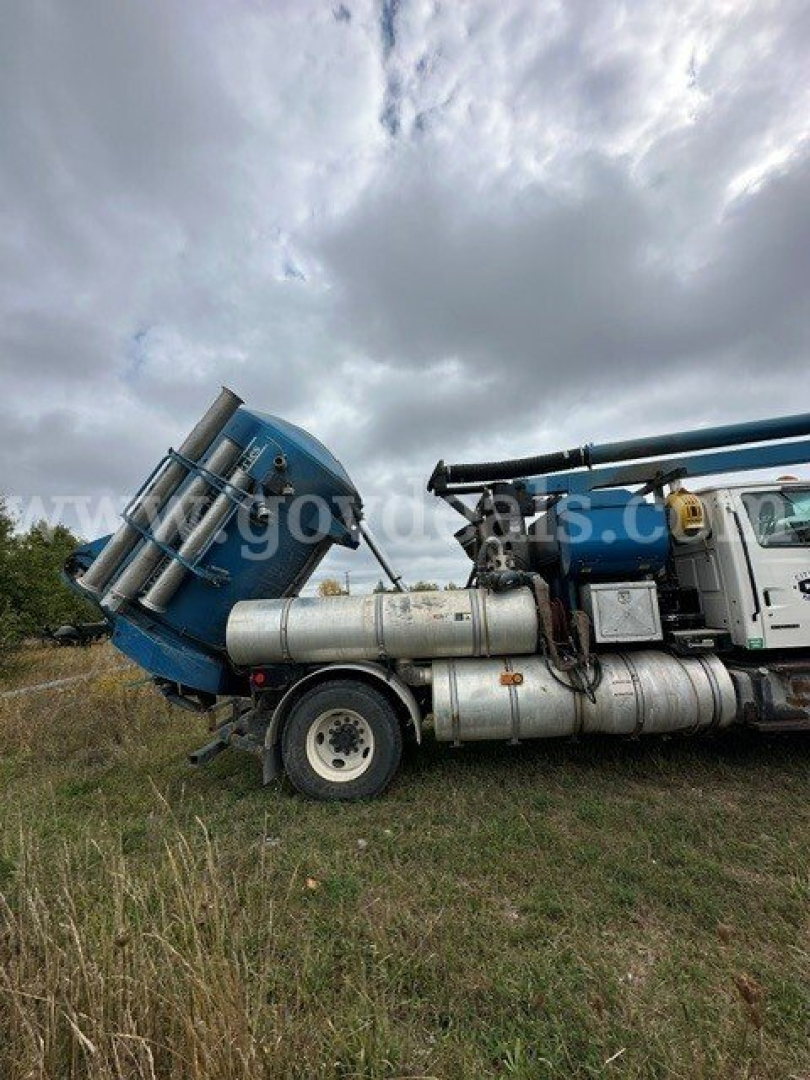 Sterling L7501 vacuum truck side view showing blue cab and large cylindrical tanks with mounted hoses and metal steps.