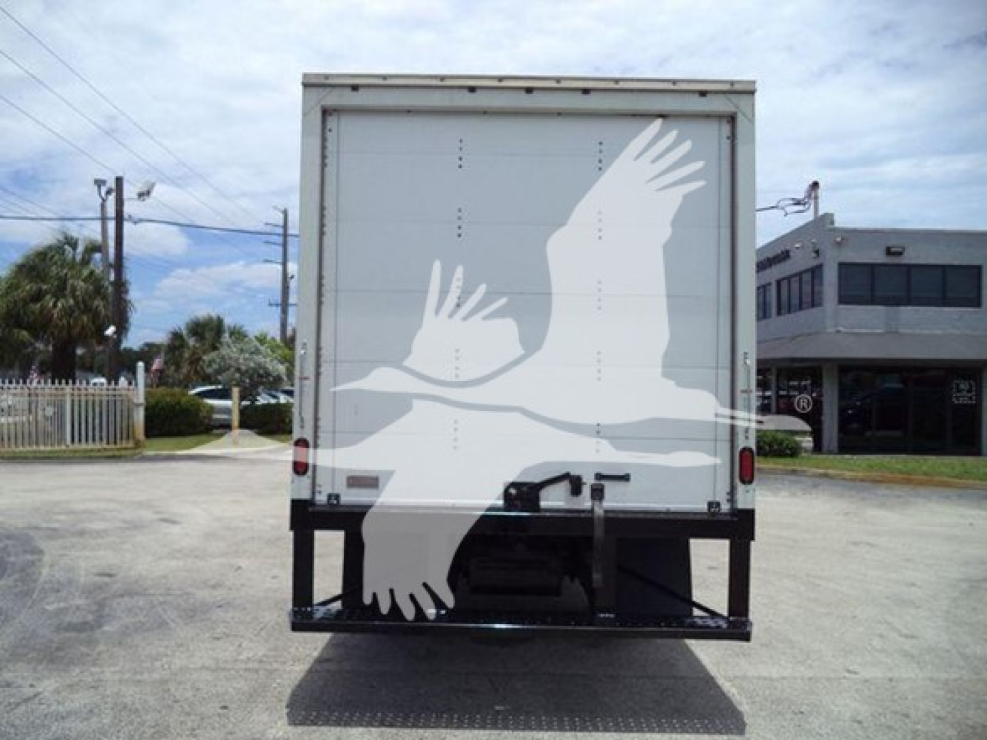 Isuzu NRR box truck rear view showing blank white back doors and a black lift bumper.